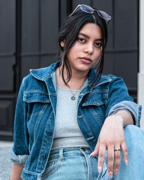 Free Stylish young woman in denim sitting casually outdoors. Stock Photo