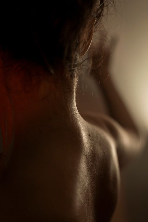 Free Artistic back view of a woman in dim light, showcasing skin texture and shadow play. Stock Photo