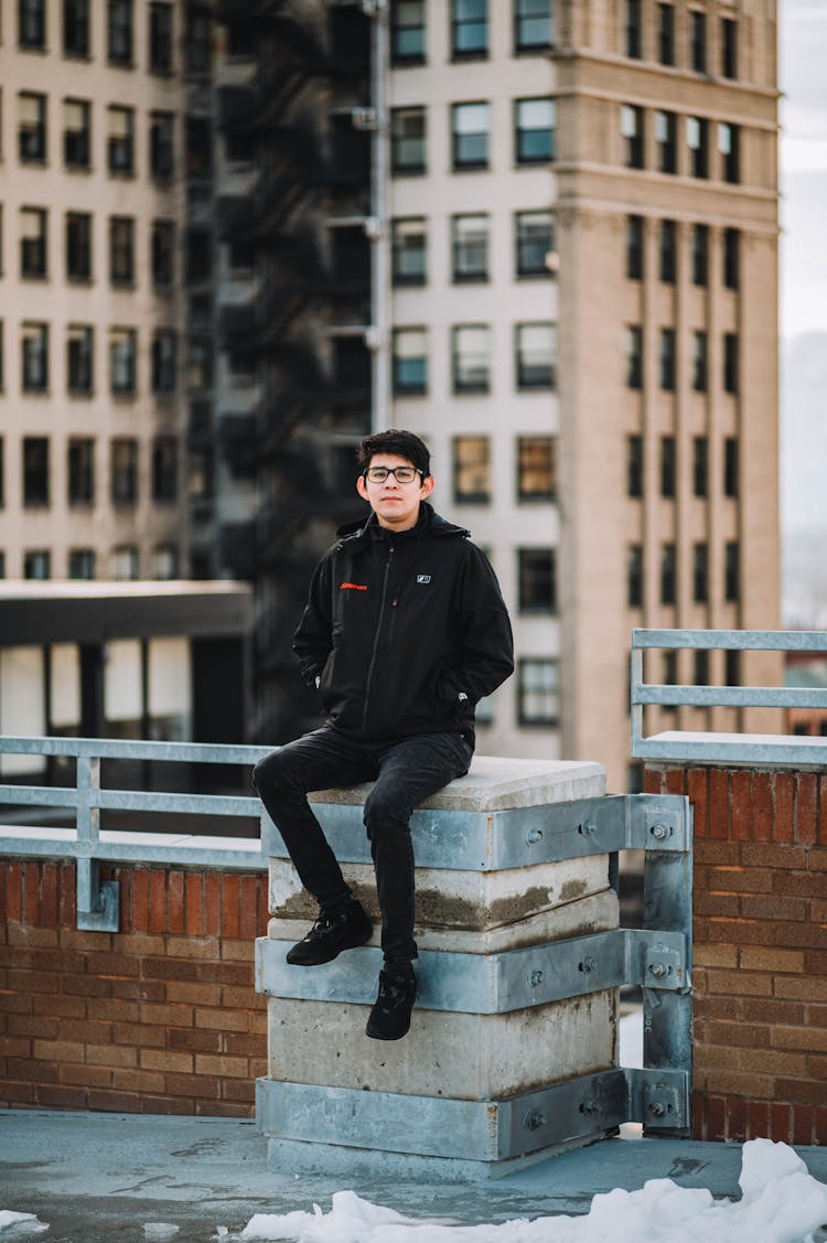 Young Man Sitting On A Terrace Of A Skyscraper 