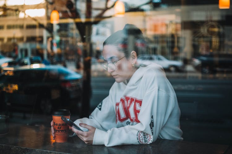 Woman In White Hoodie Holding A Cellphone