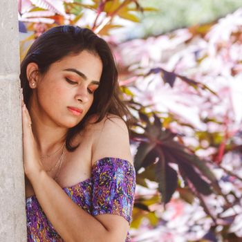 Peaceful portrait of a woman with closed eyes enjoying the outdoors in a colorful floral dress.