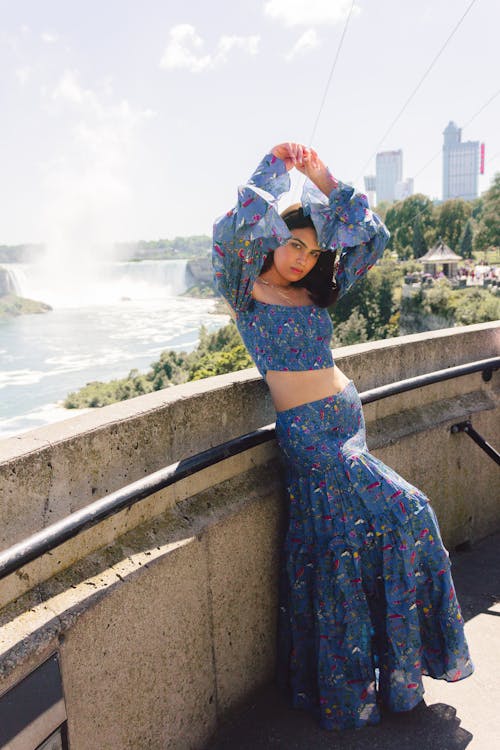 Woman Posing in Traditional Clothing by Wall near River in City