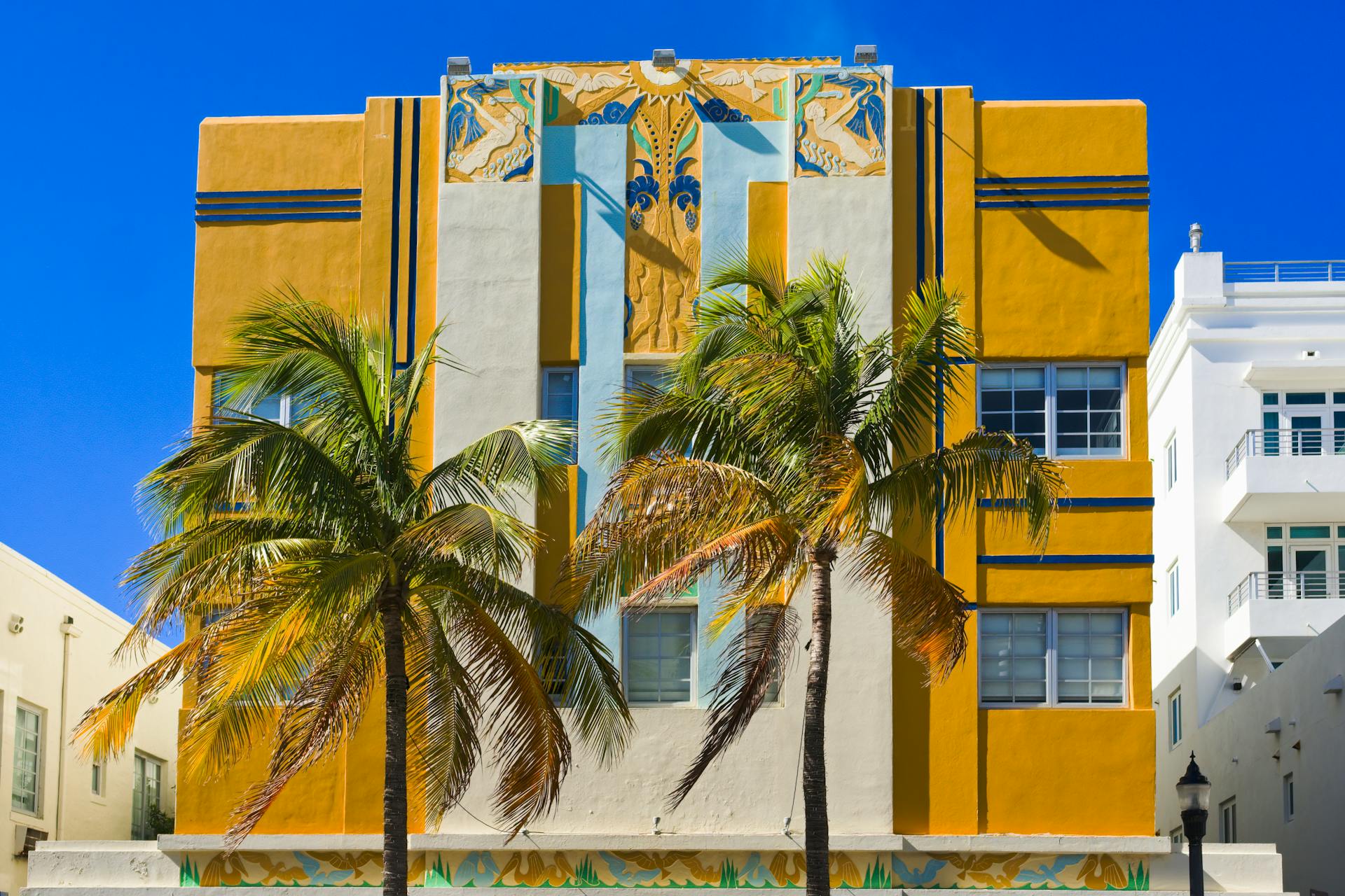 Vibrant Art Deco building with palm trees in sunny Miami Beach.