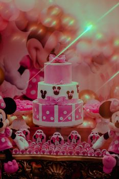 Colorful Minnie Mouse themed birthday setup with a pink cake and decorations.