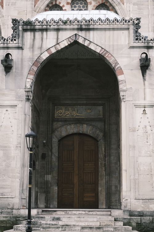 Free Detailed view of a historic mosque entrance showcasing intricate Islamic architectural elements and wooden doors. Stock Photo