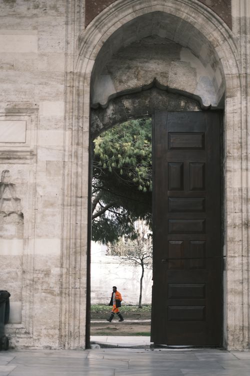 Free A historical stone archway with an open wooden door revealing a glimpse of nature. Stock Photo