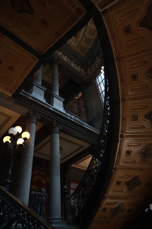 Free Elegant curved staircase with ornate details and warm lighting in a historical building. Stock Photo