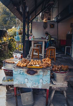 Outdoor street food stall with grilled meats and eggs in a vibrant urban environment featuring a seated customer.