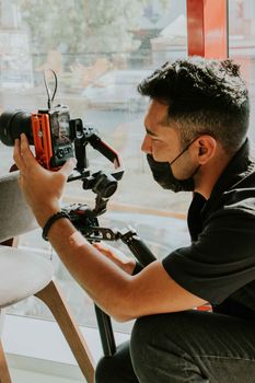 Photographer wearing face mask using camera equipment indoors for filming or photography work.