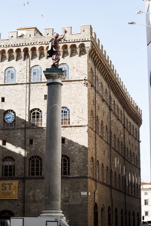 Free Statue atop a column against a historic Roman building in daylight. Stock Photo