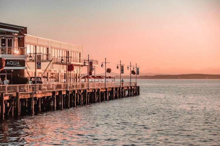 People Walking On Pier With Restaurants On Sunset