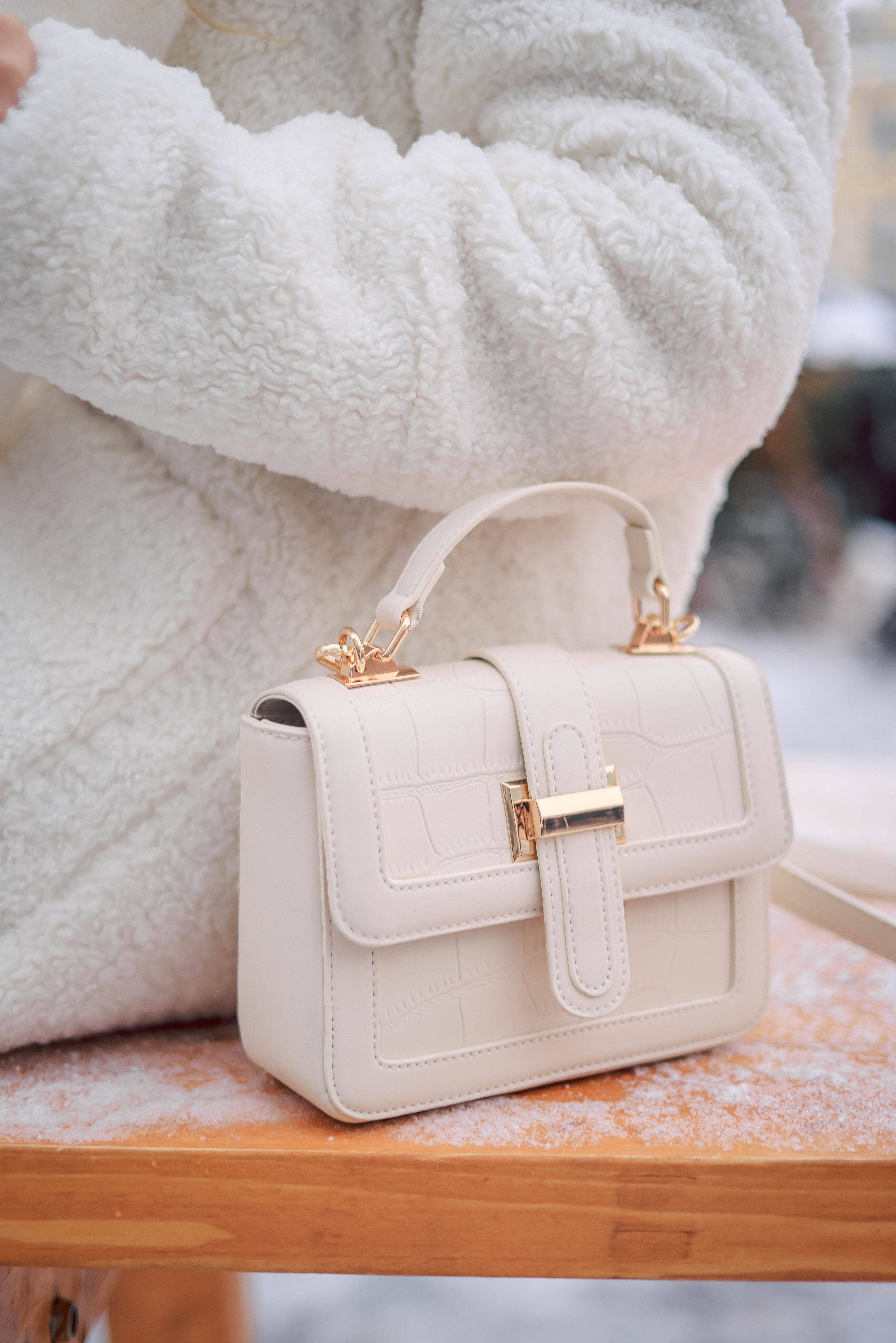 Elegante bolsa branca colocada em um banco, perfeita para a moda de inverno. Capturada com uma Canon EOS R5.