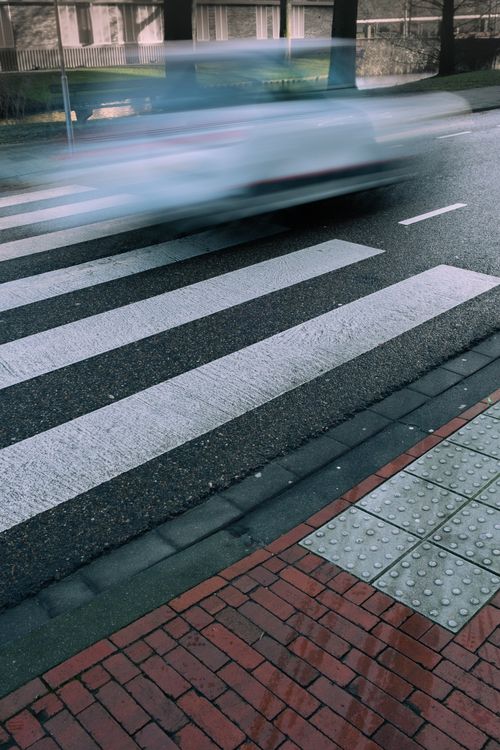 Free A blurred car moving quickly across a zebra crossing on a city street. Stock Photo