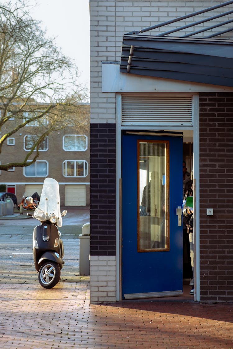 Motor Scooter Parked Beside Near The Blue Door