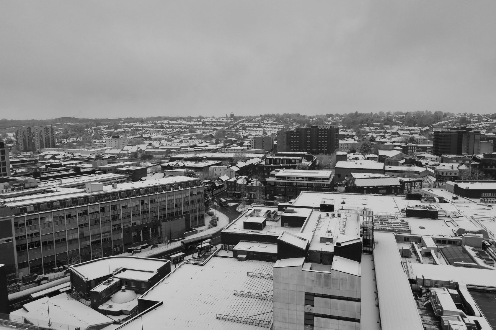 Black and white aerial view of Luton city covered in snow during winter, showcasing urban architecture.