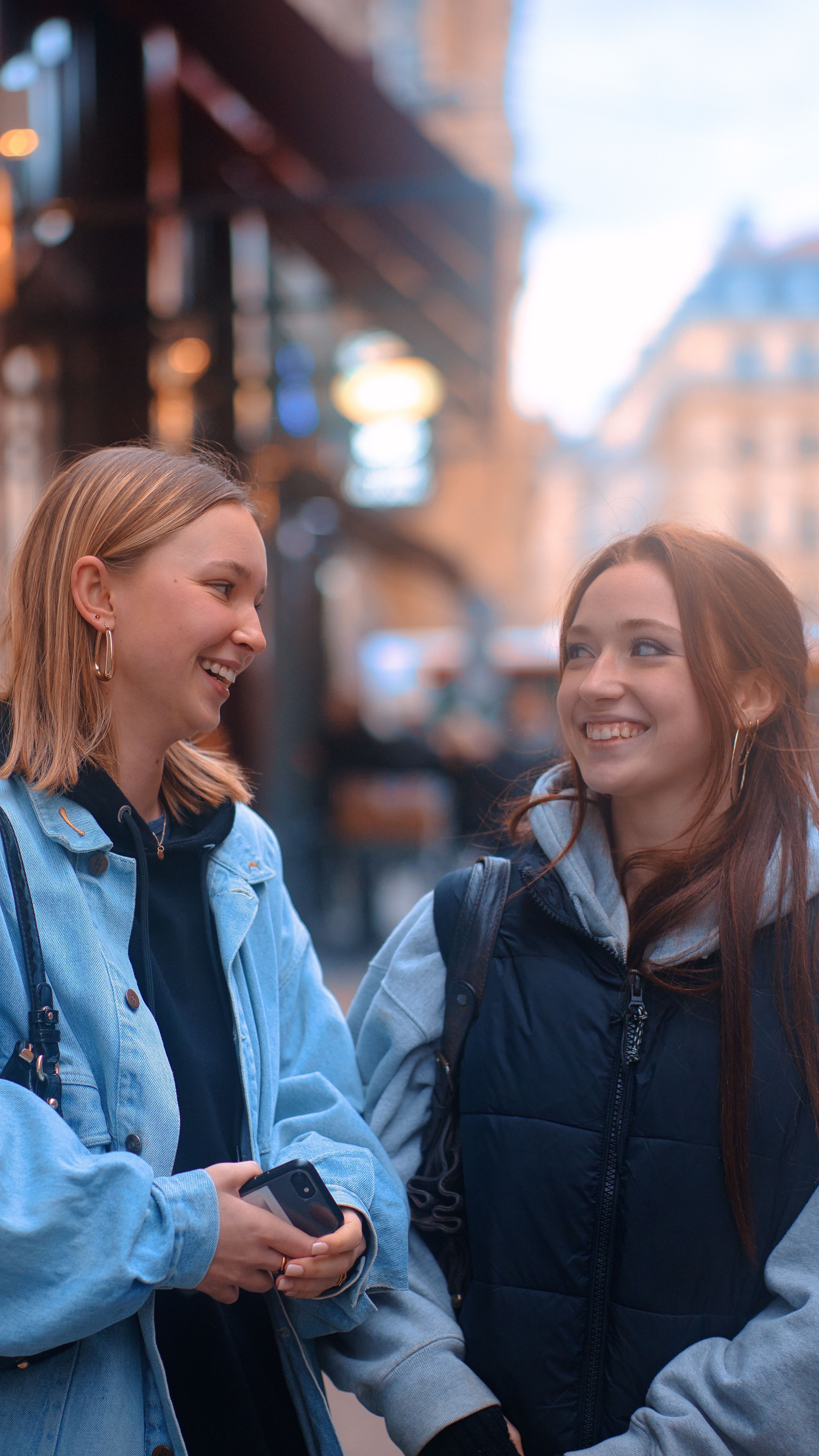 Two women laughing together on a city street