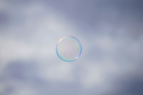 Free A solitary soap bubble gently floats against a soft, cloudy sky, epitomizing fragility and whimsy. Stock Photo