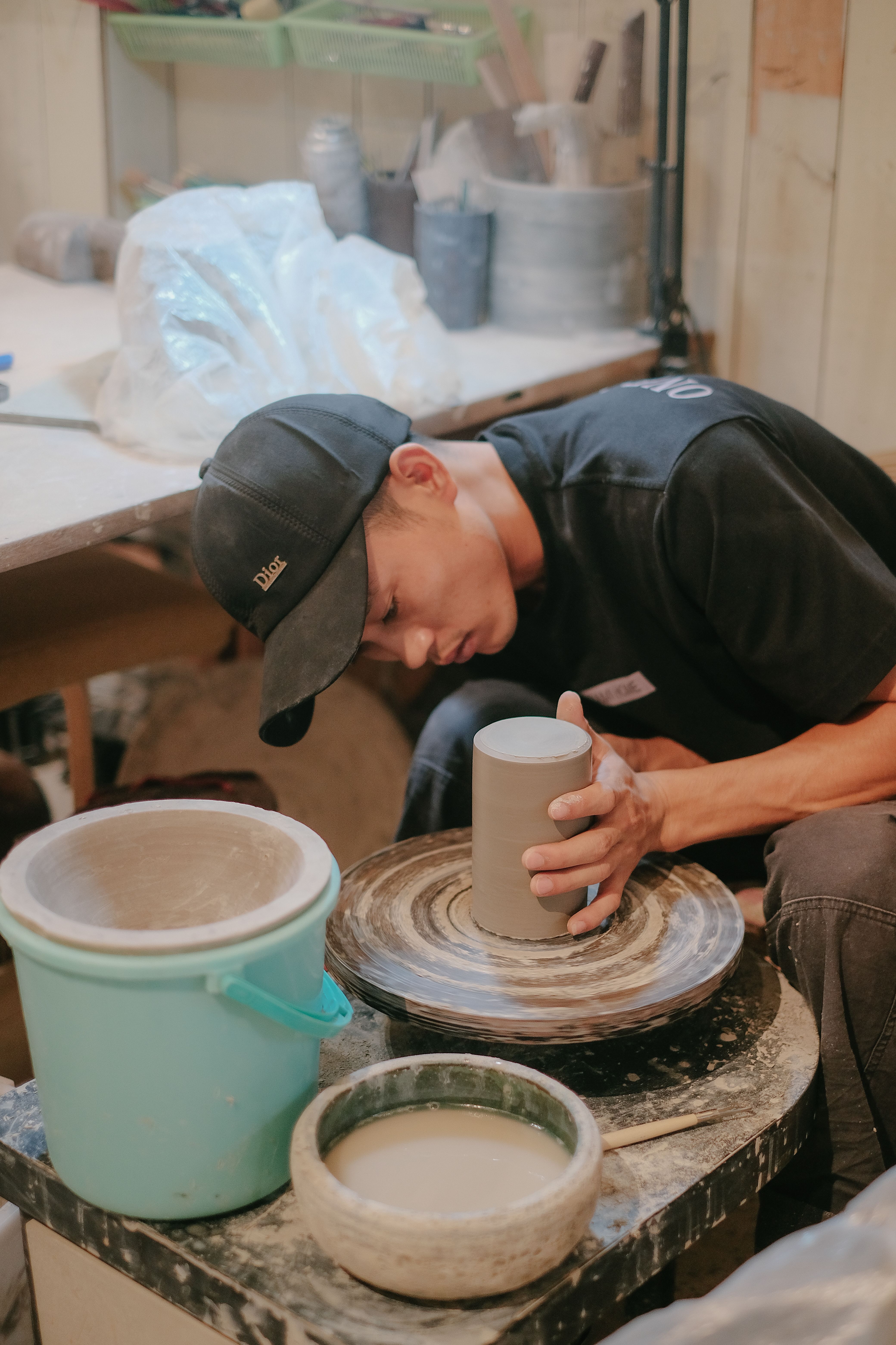 Focused artisan shaping clay into a vase on a potter's wheel in a cozy workshop.