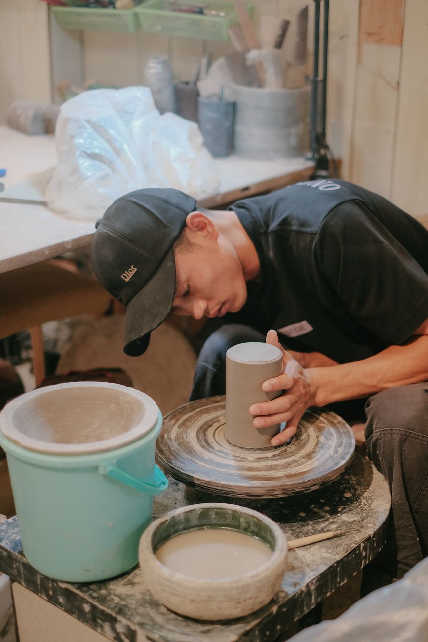 Focused artisan shaping clay into a vase on a potter's wheel in a cozy workshop.