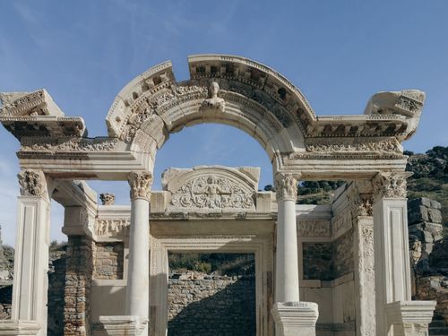 Free A stunning view of ancient Roman ruins featuring a detailed arch under a clear sky. Stock Photo