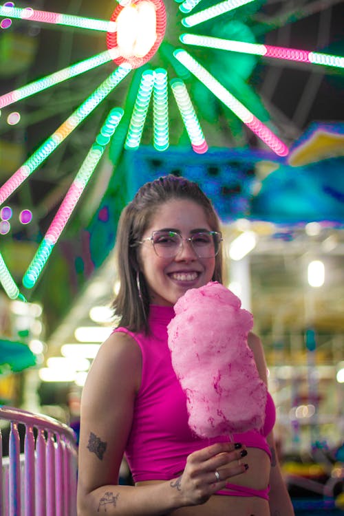 Woman Eating Cotton Candy in a Funfair 