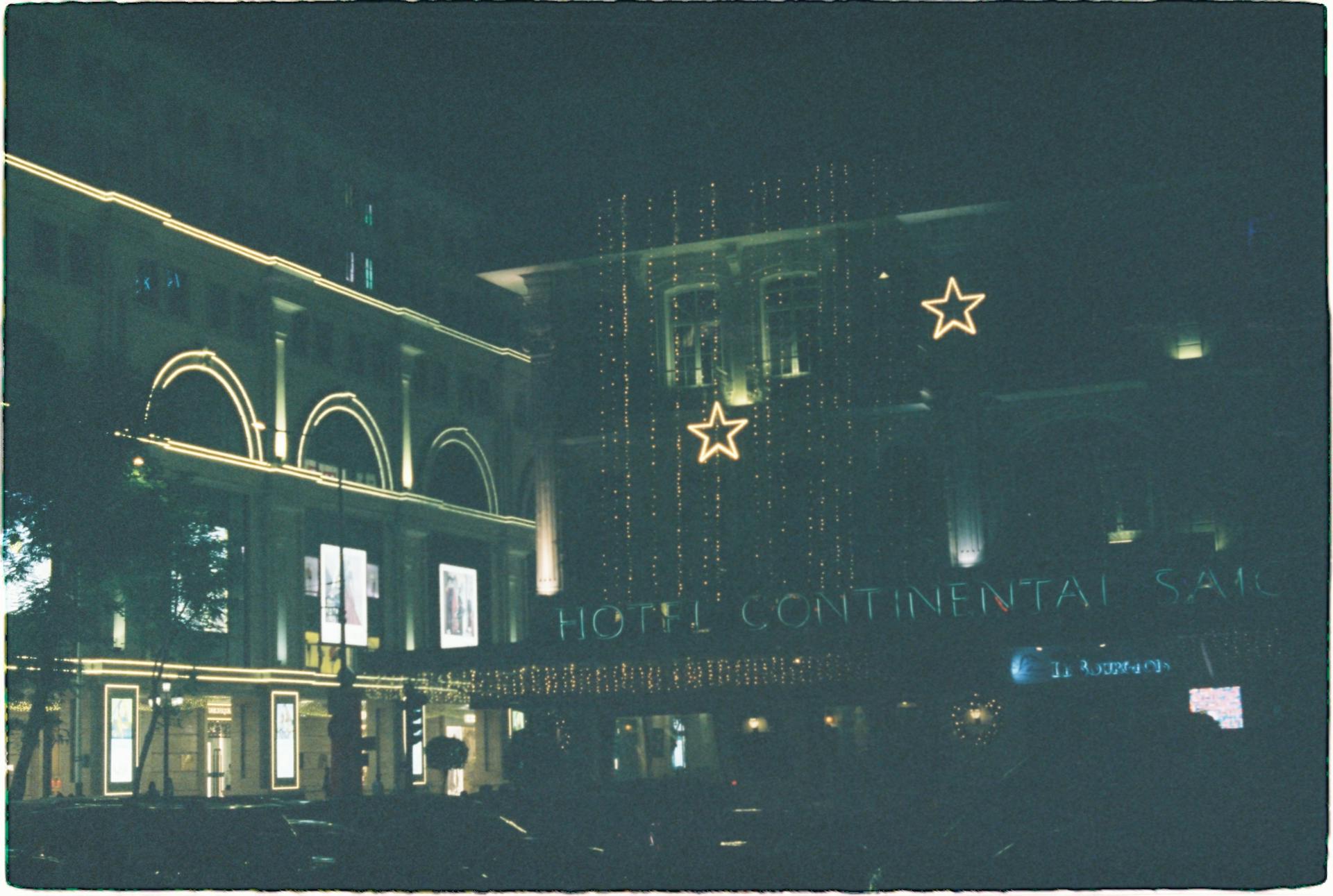 Night view of the illuminated Hotel Continental Saigon, adorned with festive lights and stars.