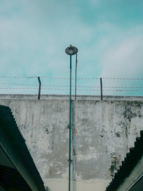 Základová fotografie zdarma na téma betonový plot, modrá obloha, ostnatý drát