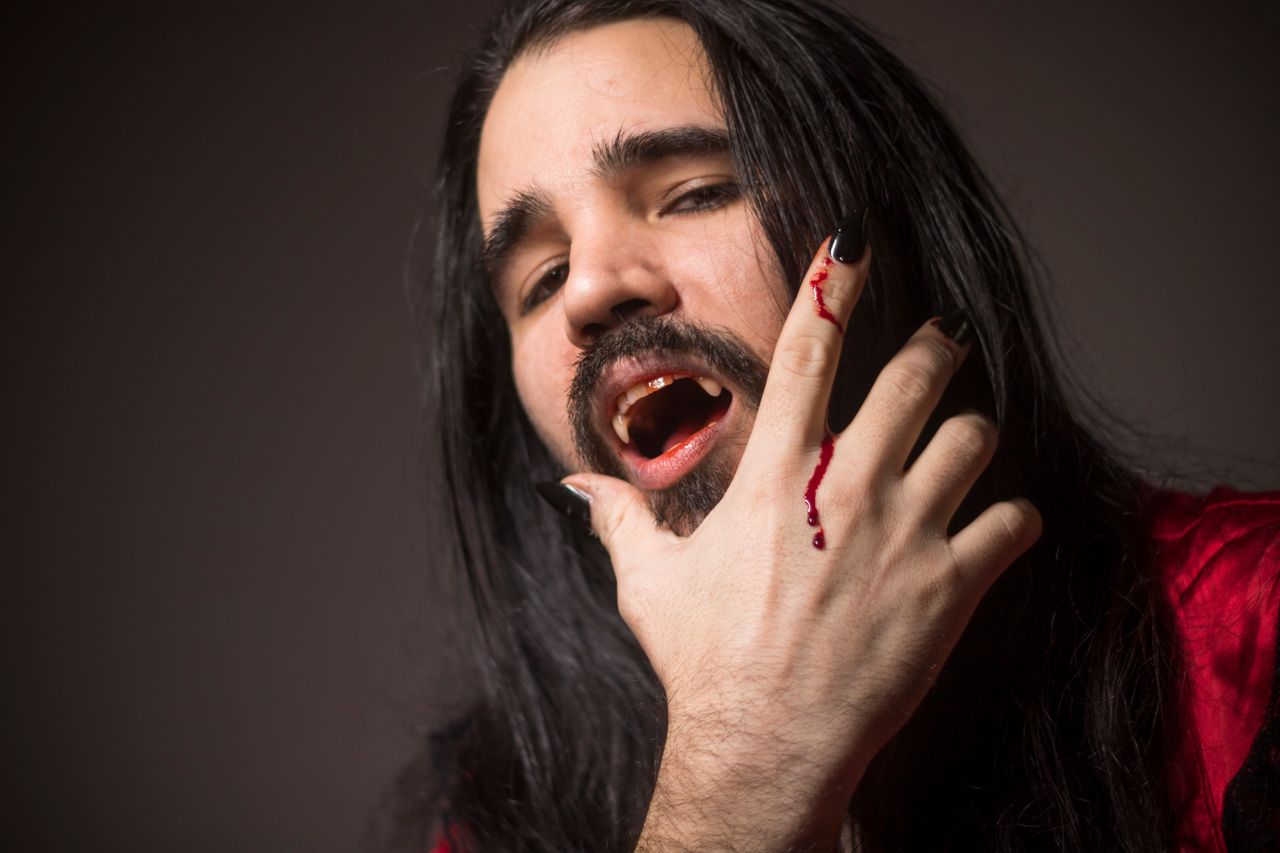 close up portrait of a man in vampire cosplay with fangs and bloodied