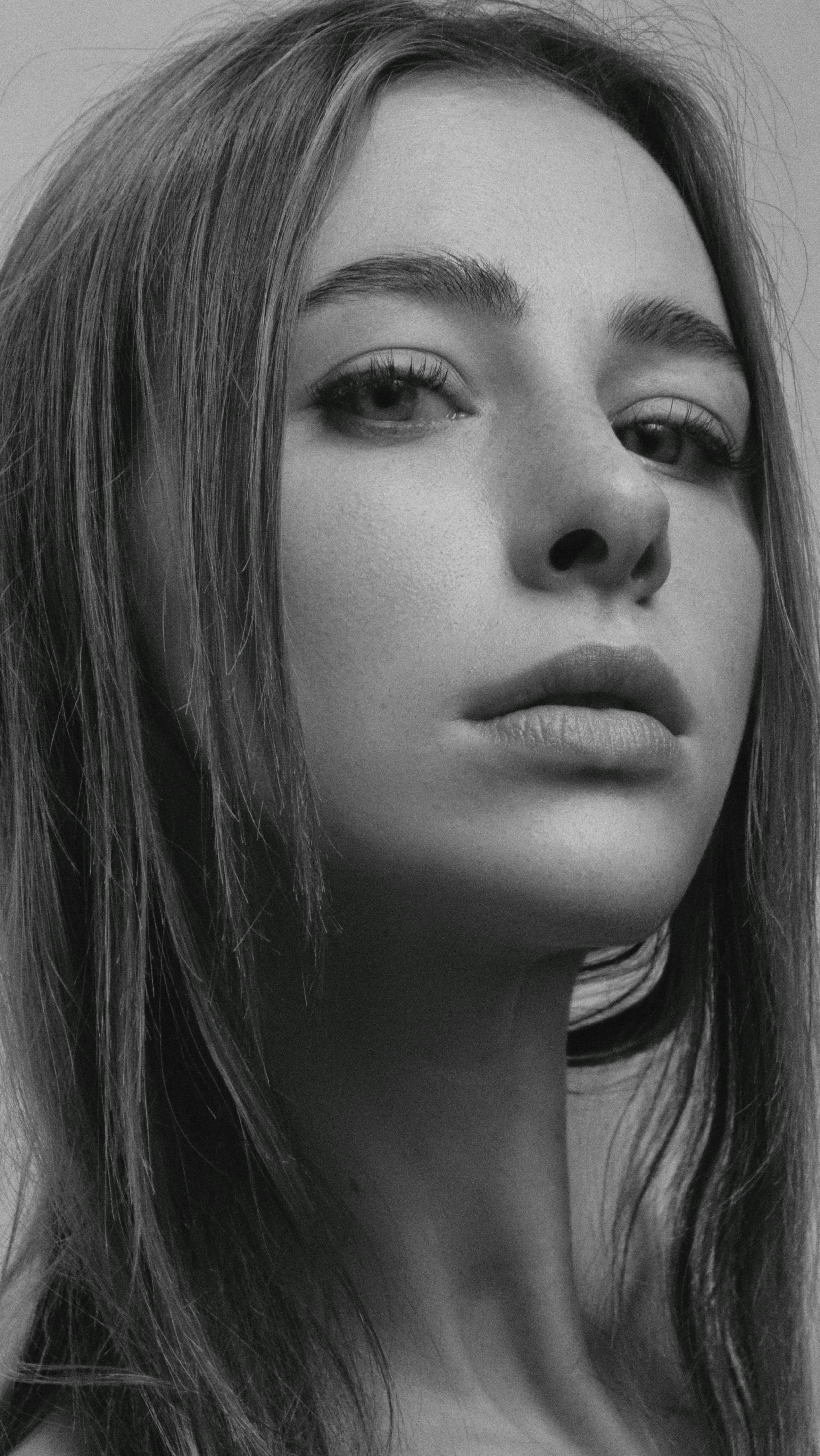 Close-up black and white portrait of a woman with long hair and expressive eyes.
