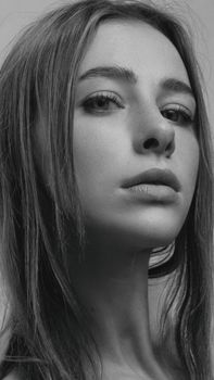 Close-up black and white portrait of a woman with long hair and expressive eyes.