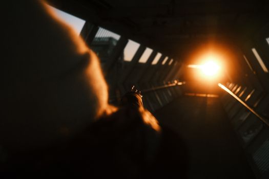 Silhouette of a person pointing towards a glowing sunset in an urban tunnel.