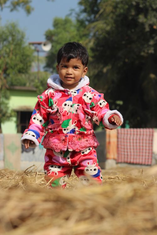 Free A cute child in a colorful jacket standing in a playful outdoor setting. Stock Photo