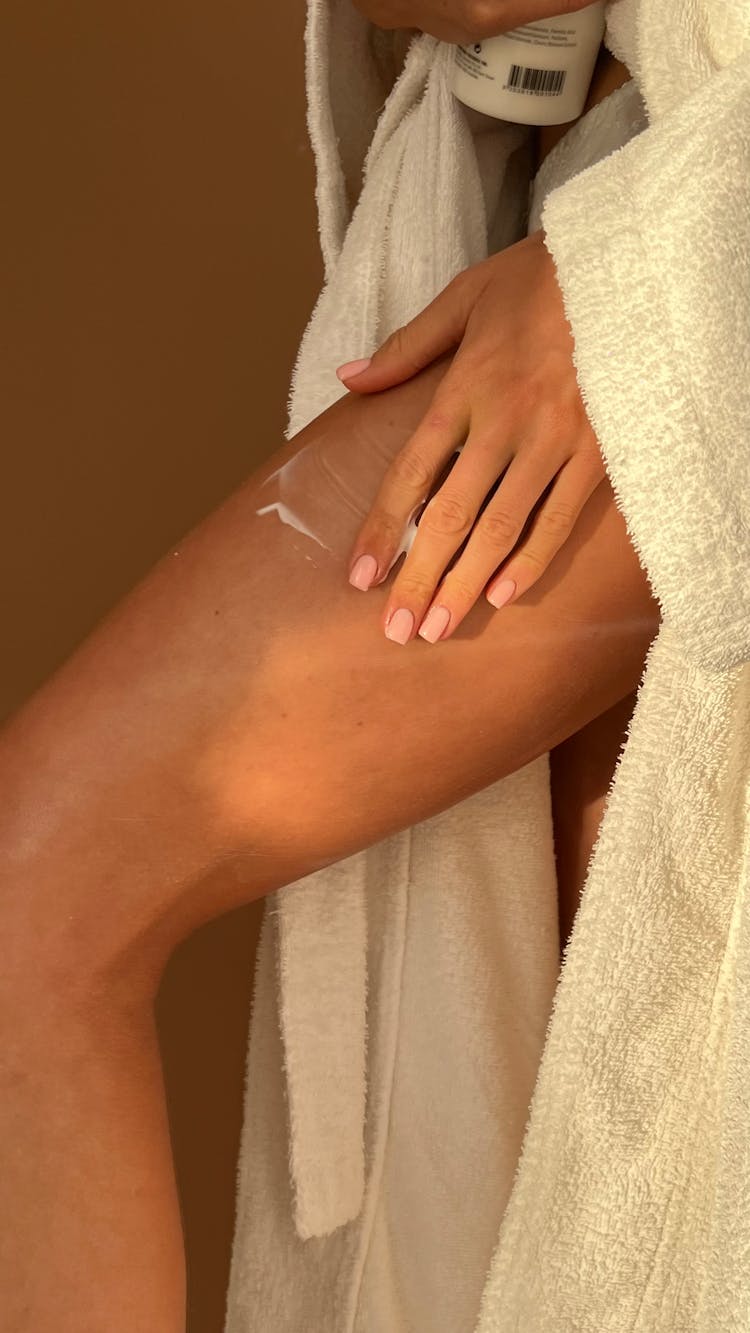 Woman Applying Lotion On Her Thigh