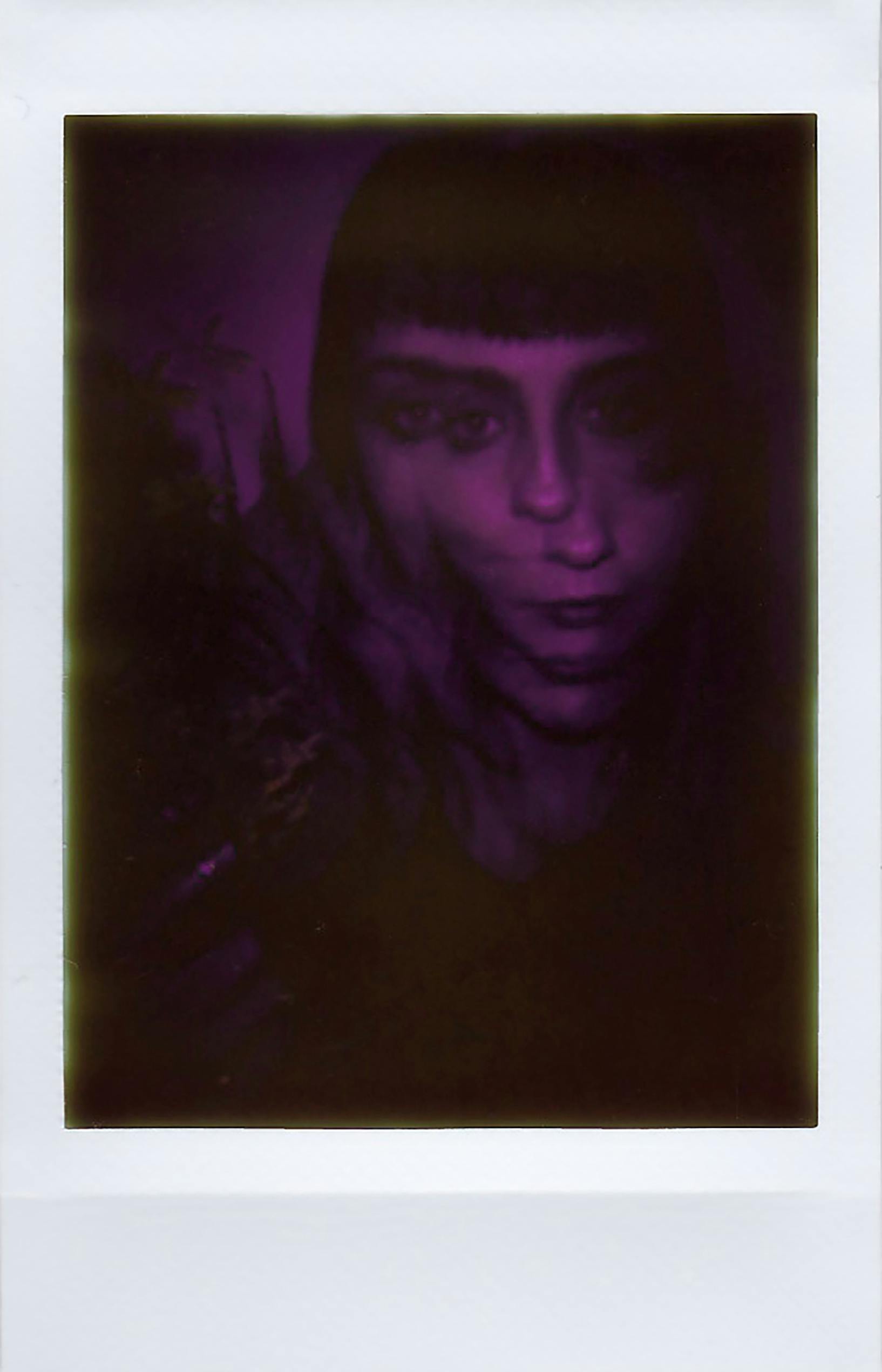 A mysterious double exposure portrait of a woman with a purple hue, creating an ethereal effect.