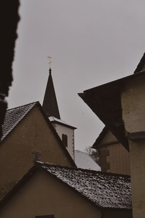 Church Tower behind Buildings Walls and Roofs