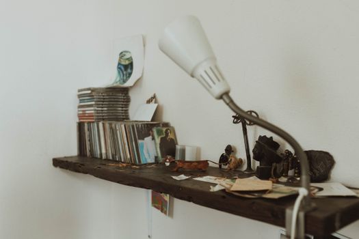 Cozy shelf with stacked CDs, artworks, and a decorative lamp for a vintage aesthetic.