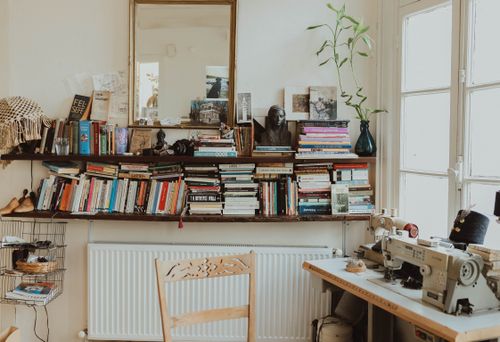 Free Warm and inviting home office featuring a sewing machine, bookshelves, and vintage decor. Perfect for creative inspiration. Stock Photo