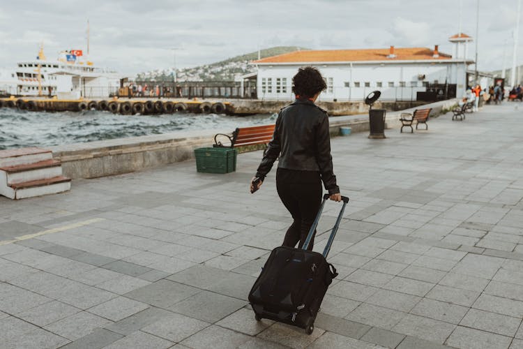 Woman Walking With Suitcase On Coast In City In Turkey