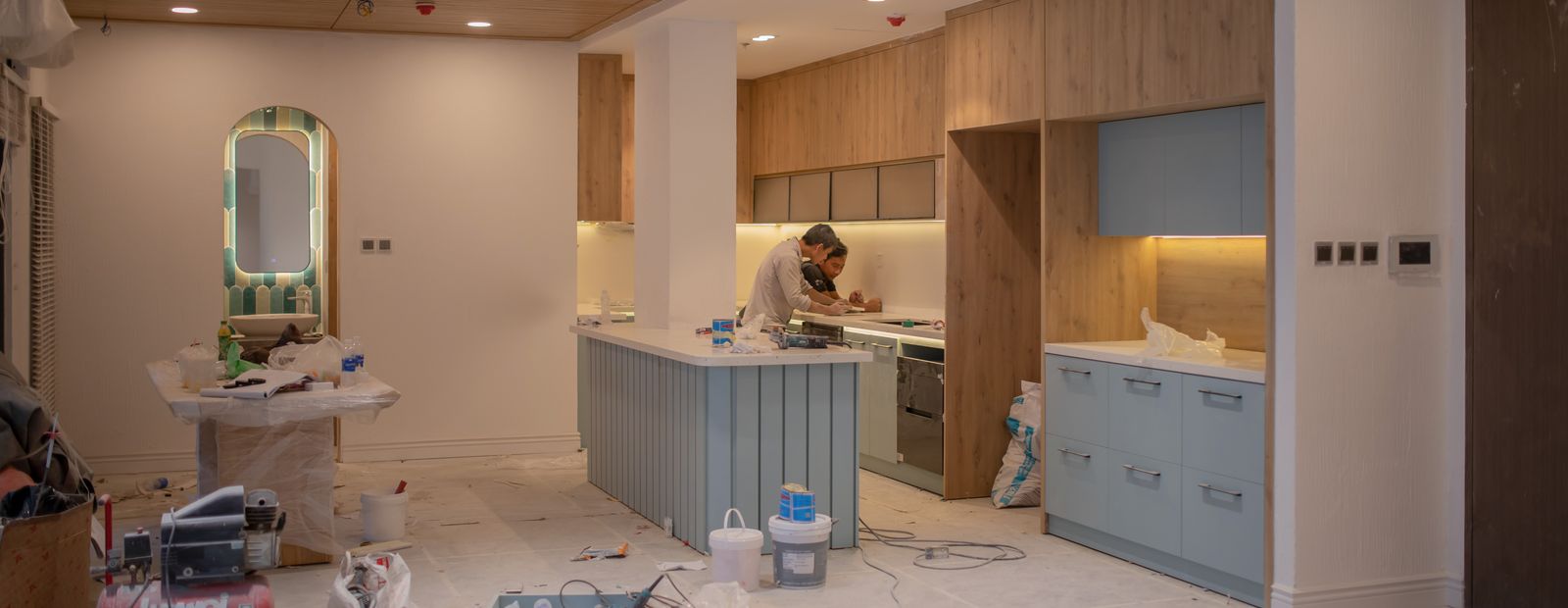 Kitchen under renovation with a worker and tools