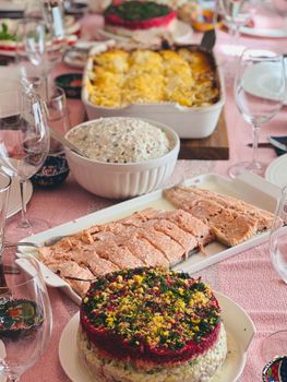 A vibrant dining table set with fresh salmon, layered salads, and potato casserole, perfect for a festive meal.