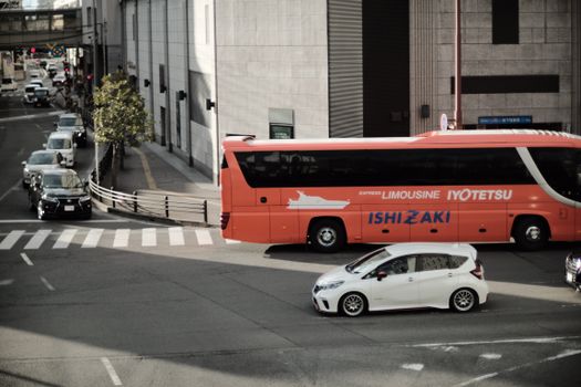 A busy city intersection with an orange bus and cars on the road.