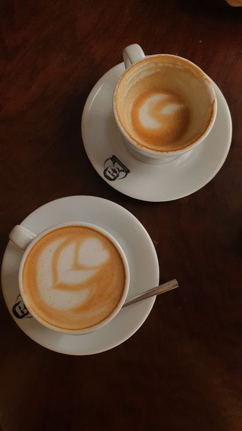 Free Two cups of coffee with intricate latte art on a wooden table, creating a cozy cafe vibe. Stock Photo