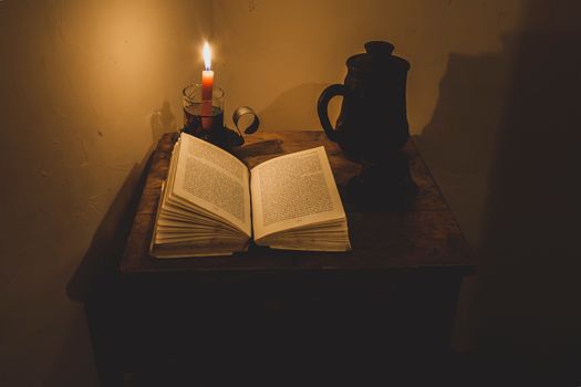 A candle and an open book on a table
