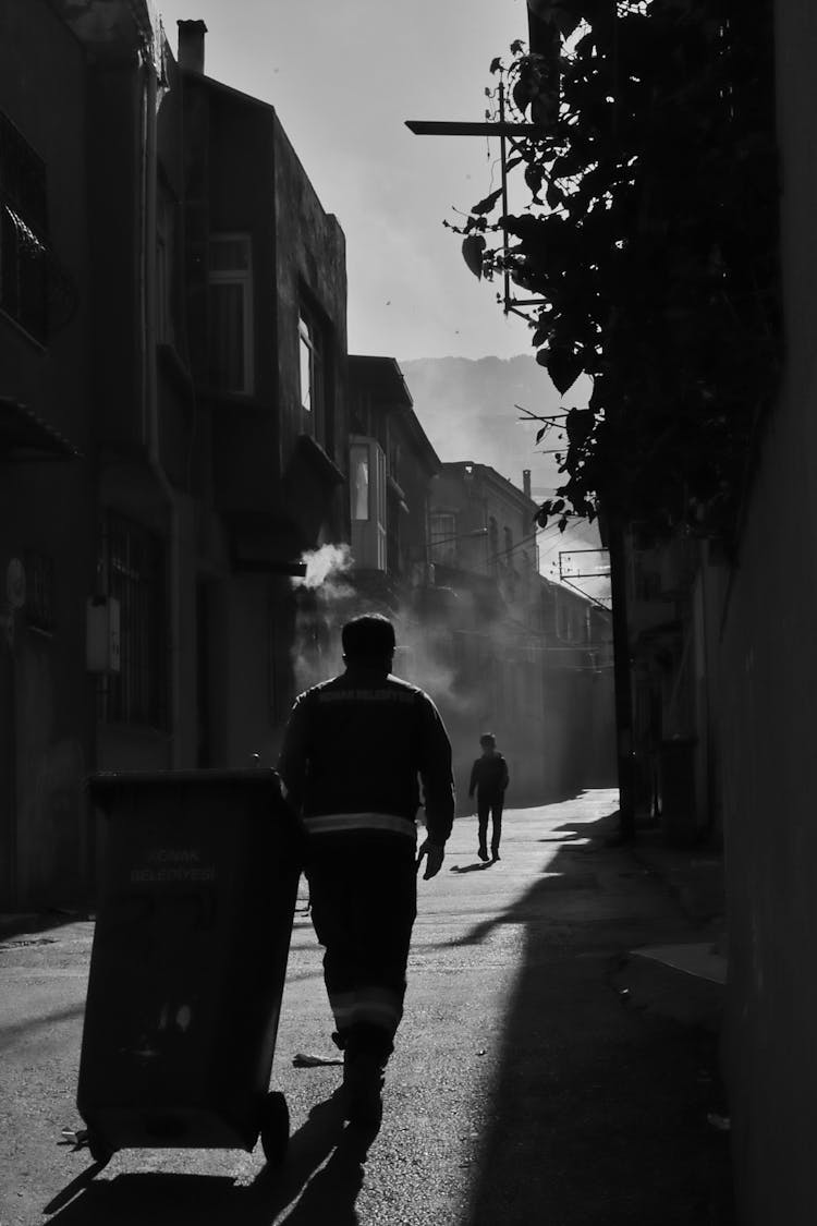 Man Walking On Street With Trash Can