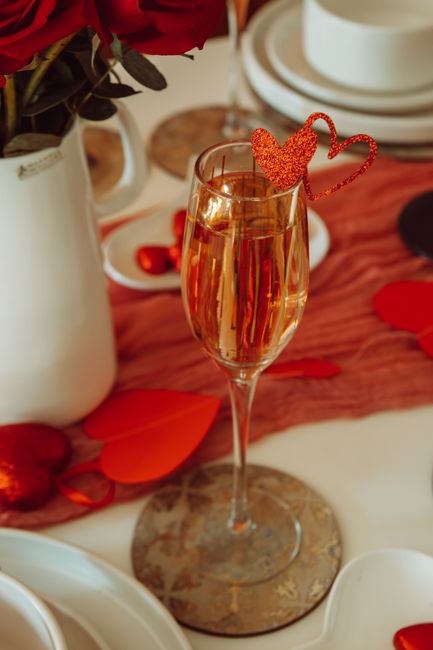 Champagne glass with heart decoration on romantic table setting.