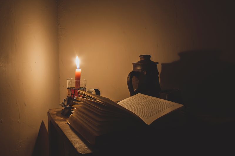 A moody candlelit table set with an open book and a vase — photo by Arturo Anez on Pexels