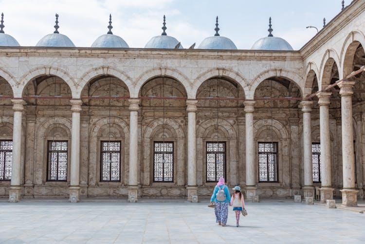 Woman And Child Walking Near Traditional Mosque