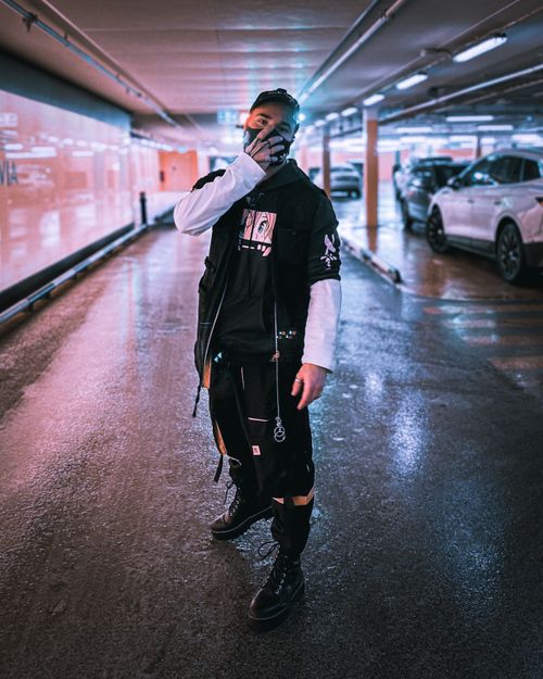 Free Portrait of a man wearing a mask in a neon-lit parking garage, creating an edgy urban vibe. Stock Photo