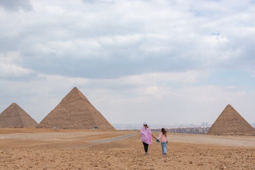 Clouds over Mother and Daughter Walking towards Pyramids