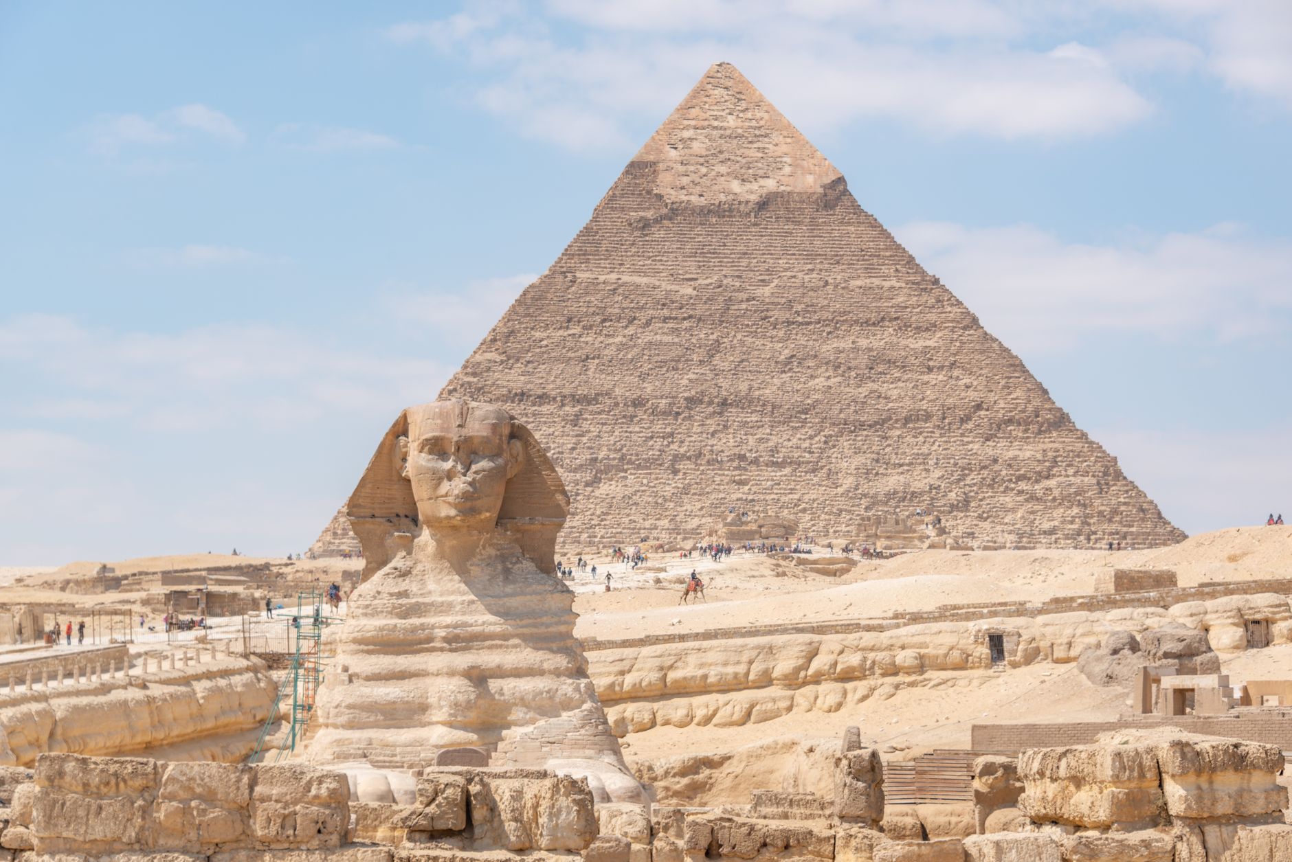 Iconic Great Sphinx and Pyramid of Khafre under a bright daytime sky in Giza, Egypt.